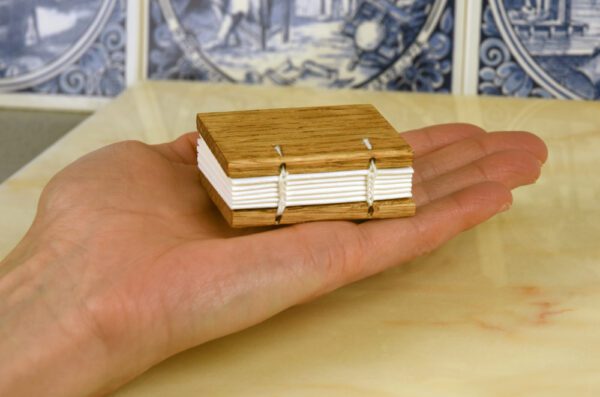 A small book is held in someones hand.