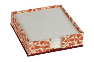 A red and white paper holder with a note pad on top of it.