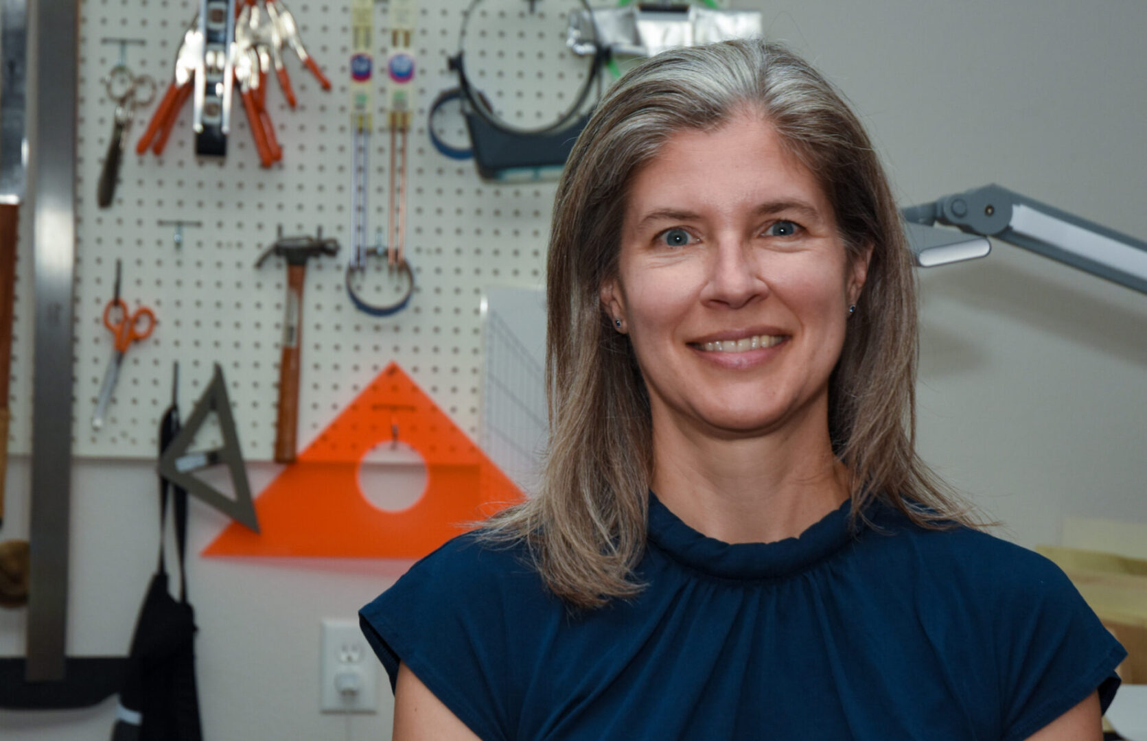 Smiling woman in blue shirt in workshop.