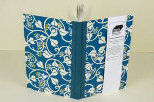 Here's an alt tag for the image: Blue floral hardback notebook open.