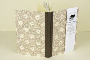 Beige hardback notebook with floral pattern.
